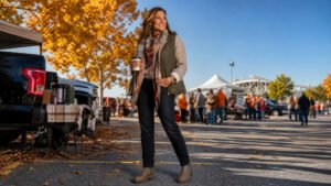woman in her late 30s in a quilted vest, blanket scarf and chunky boots at a fall football tailgate